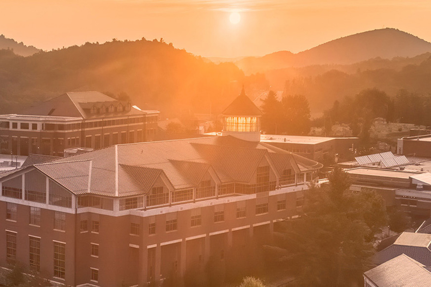 Sunrise over a mountain town with App State buildings glowing in warm golden morning light.
