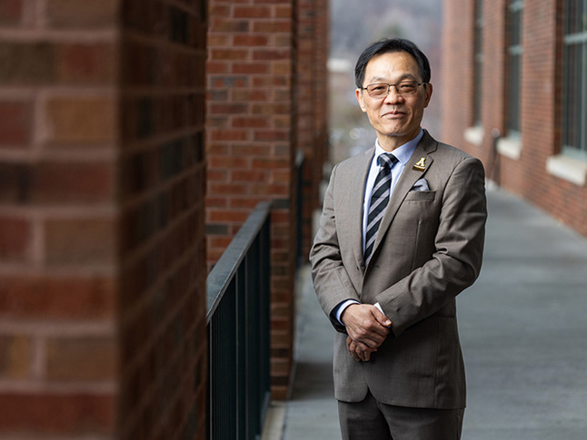 Charlie Chen with hands crossed in a suit.